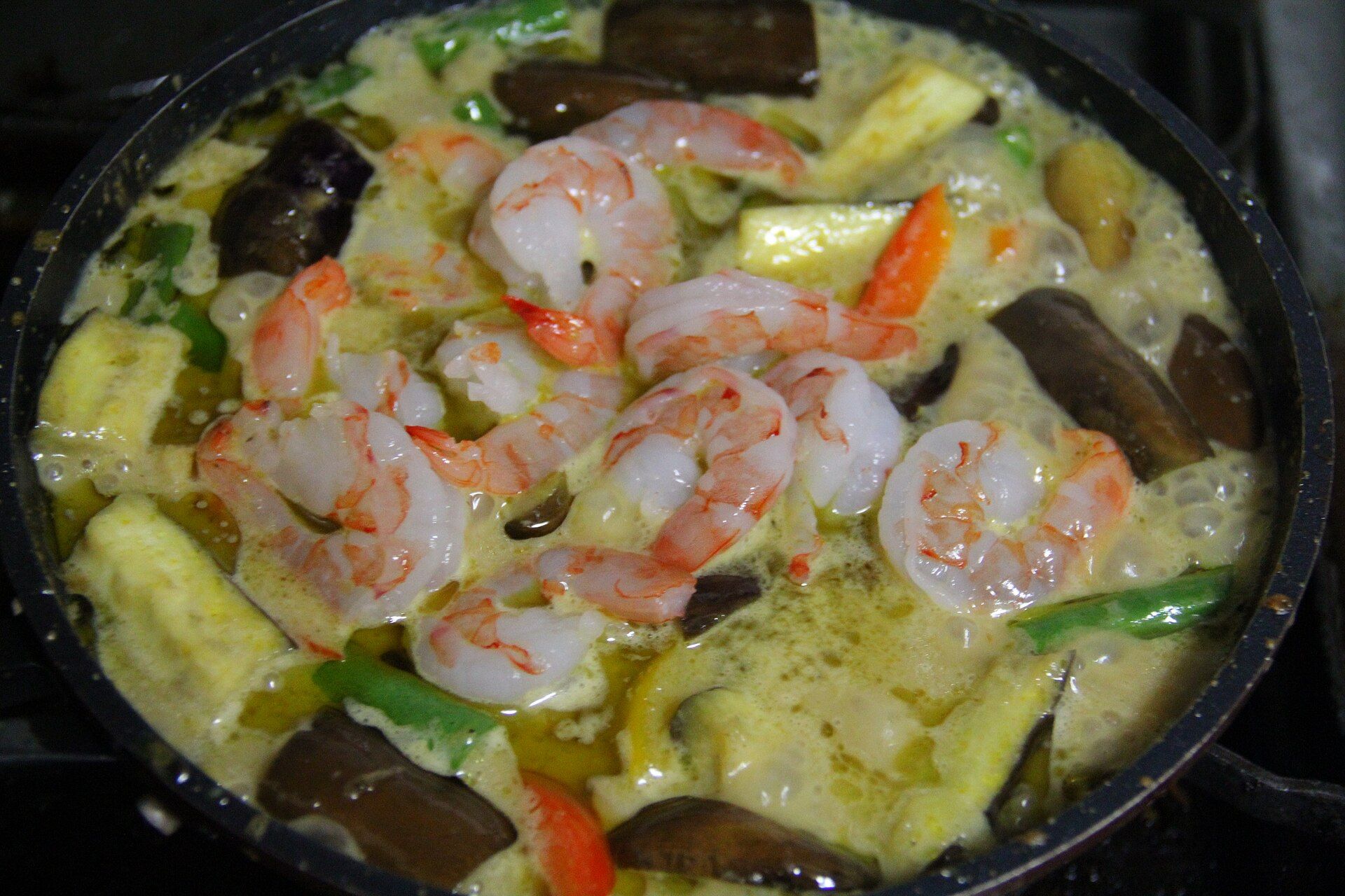 Un curry vert aux crevettes, ananas et aubergines dans une poêle